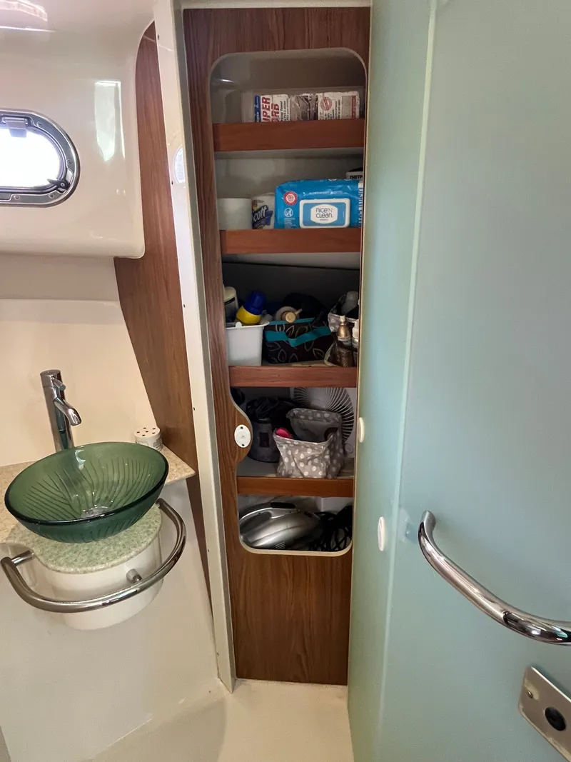 Slide: The Image of 2010 Pursuit OS 345 Offshore bathroom with glass sink and storage shelves. - 29