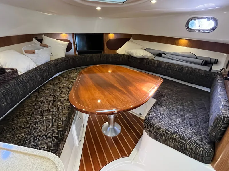 Slide: The Image of 2010 Pursuit OS 345 Offshore cabin with elegant wood table and cushioned seating. - 32