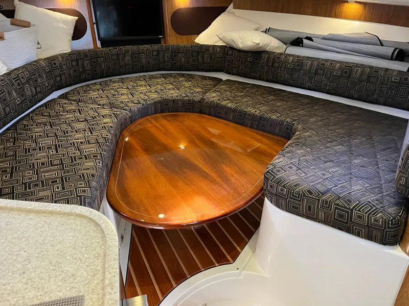 Slide: The Image of 2010 Pursuit OS 345 Offshore cabin with patterned seating and wooden table. - 34