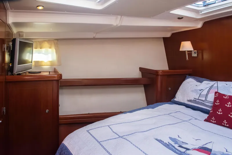 Slide: The Image of Cozy cabin interior of 2007 Beneteau Oceanis 523 with nautical-themed bedding and TV. - 5