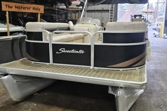 Slide: The Image of 2013 Sweetwater SW 2286 pontoon boat in storage, featuring beige seating and black exterior. - 5