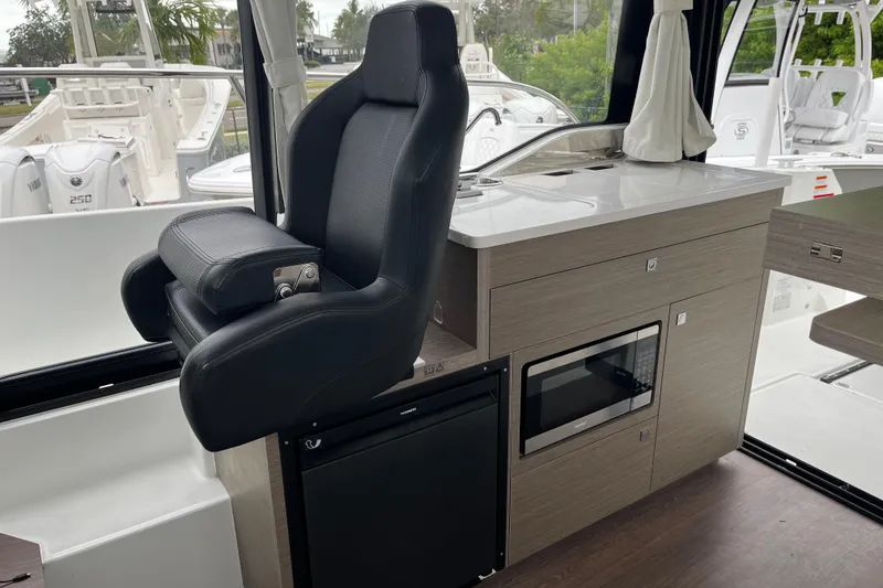 Slide: The Image of Interior of 2025 Jeanneau NC 895 Sport Series 2, featuring helm seat and kitchenette. - 13