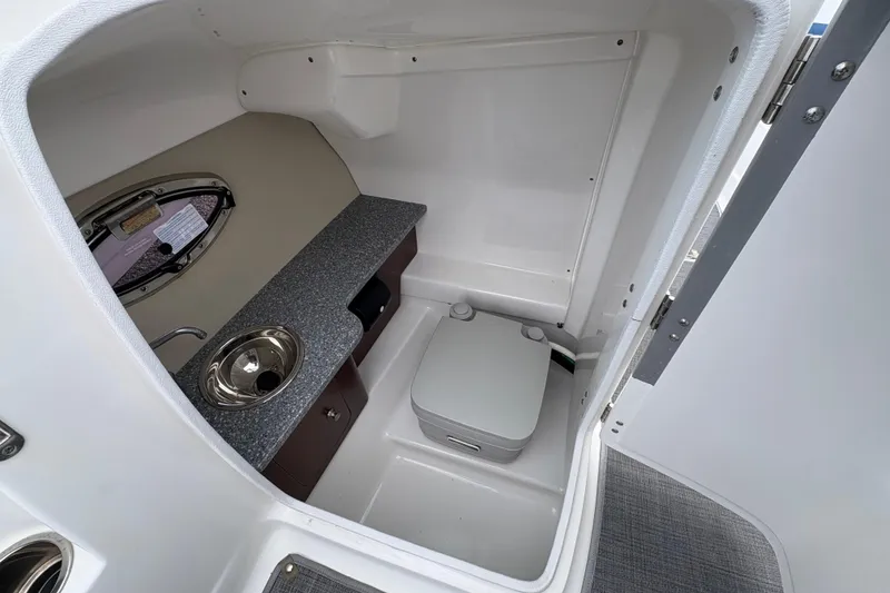 Slide: The Image of 2015 Chaparral 264 Sunesta boat interior with compact bathroom and sink. - 13