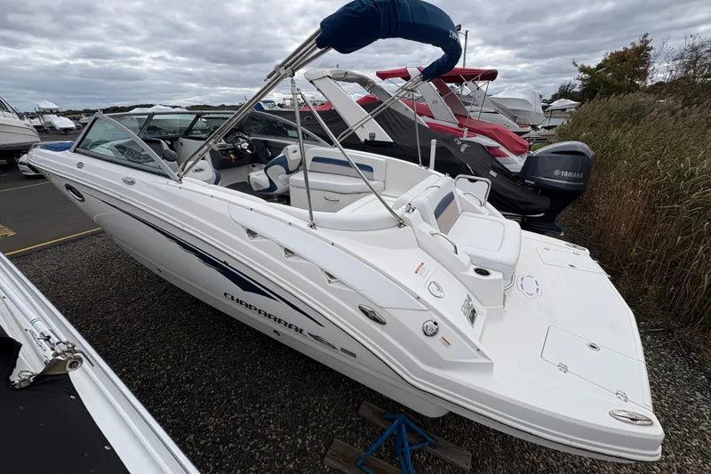 Slide: The Image of 2015 Chaparral 264 Sunesta boat with blue cover, parked outdoors. - 2