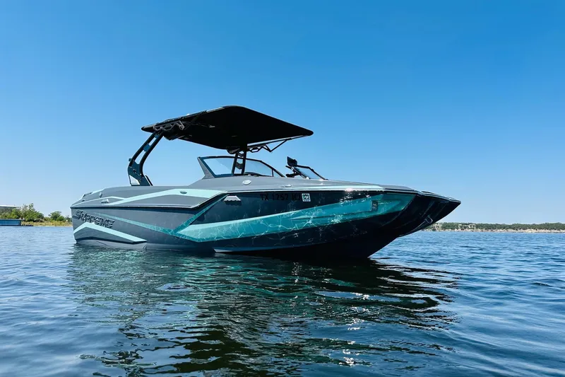 Slide: The Image of 2021 Supreme ZS232 boat on calm water under clear blue sky. - 2