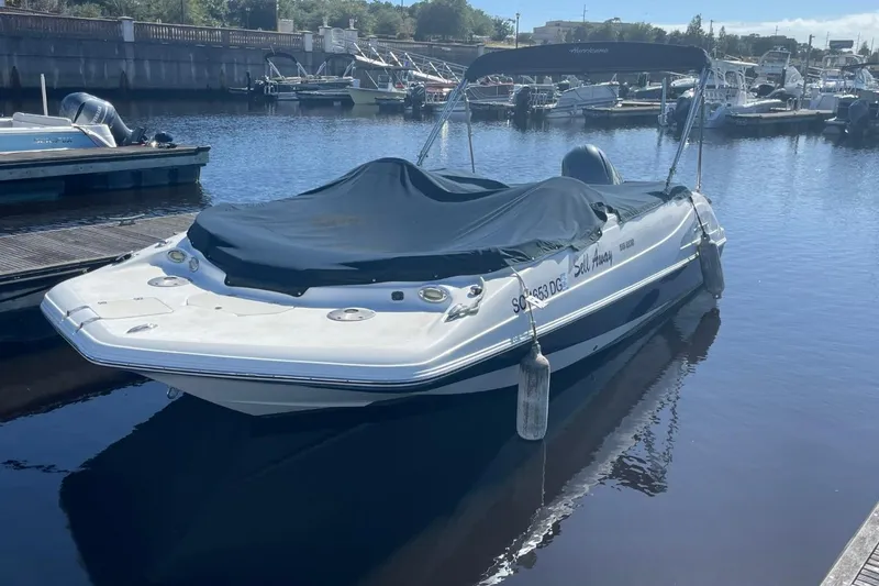 The Image of 2017 Hurricane SunDeck Sport 202 OB boat docked with cover on, in a marina setting. - 0