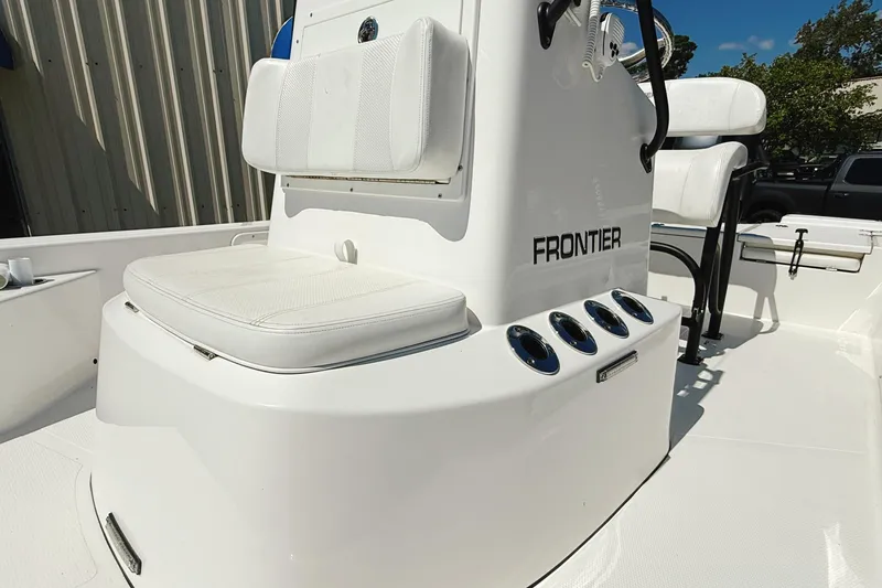Slide: The Image of 2023 Frontier 2104 boat interior with steering console and seating, outdoors under clear sky. - 20