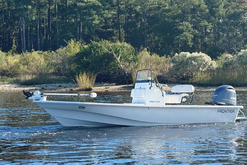 Slide: The Image of 2023 Frontier 2104 boat with Yamaha outboard motor, parked outdoors on a sunny day. - 28