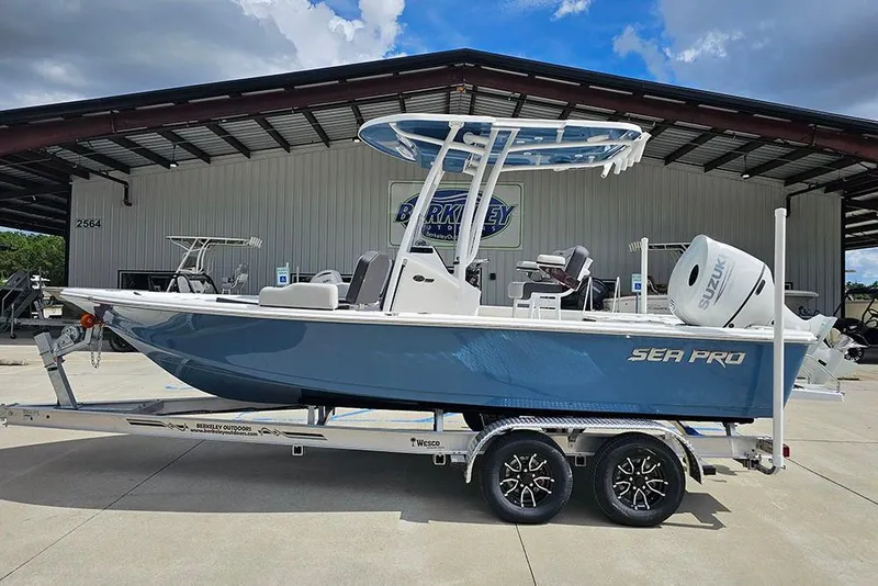 The Image of 2026 Sea Pro 210 Bay boat on trailer, displayed outdoors under a metal roof. - 1