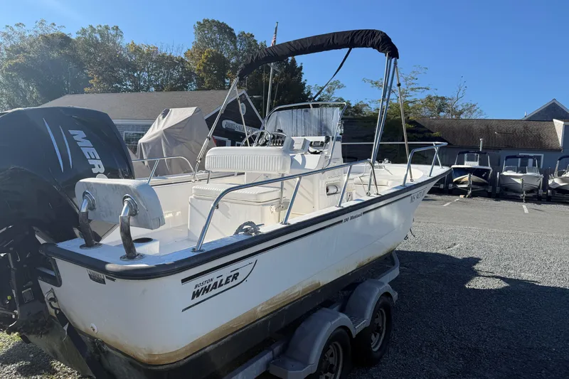 Slide: The Image of 2014 Boston Whaler 190 Montauk boat on trailer, parked outdoors under clear sky. - 2