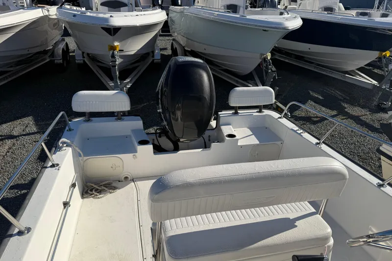 Slide: The Image of 2014 Boston Whaler 190 Montauk boat interior with motor, parked among other boats. - 8
