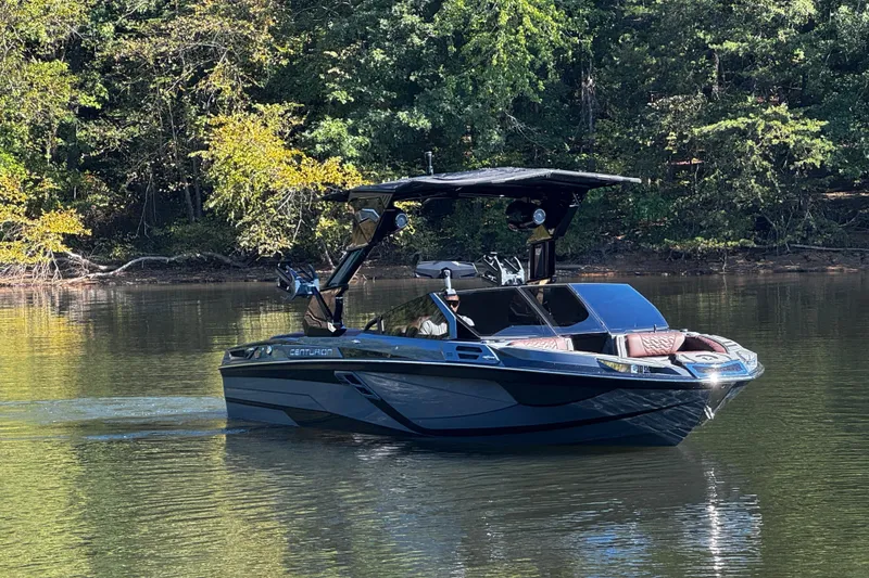 Slide: The Image of 2026 Centurion Ri230 boat on a calm lake surrounded by trees. - 2