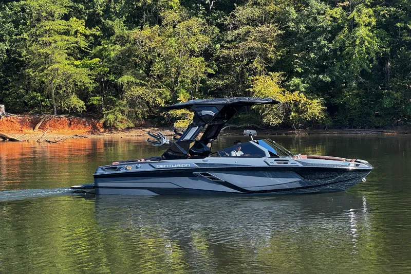 Slide: The Image of 2026 Centurion Ri230 boat cruising on a serene lake with lush forest backdrop. - 3
