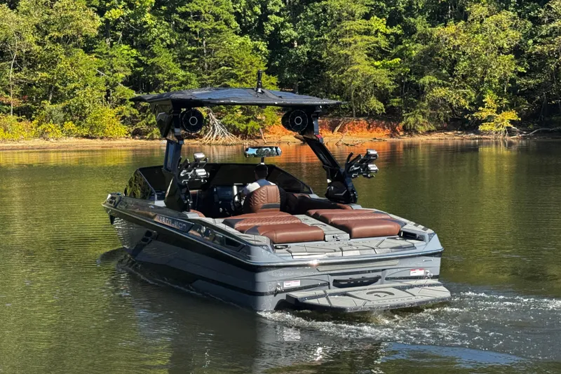 Slide: The Image of 2026 Centurion Ri230 boat cruising on a serene lake surrounded by lush greenery. - 7