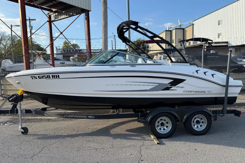 Slide: The Image of 2022 Chaparral 21 SSi boat on trailer, parked outdoors near industrial buildings. - 1