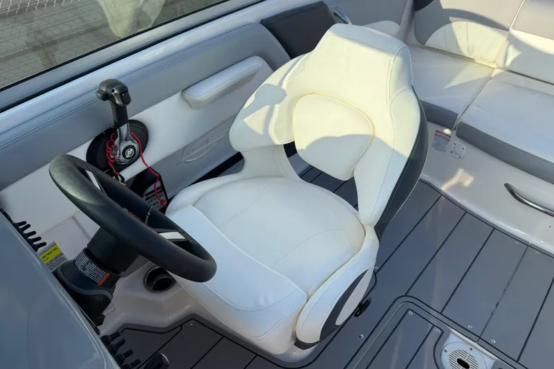Slide: The Image of 2022 Chaparral 21 SSi boat interior with white captain's chair and steering wheel. - 21