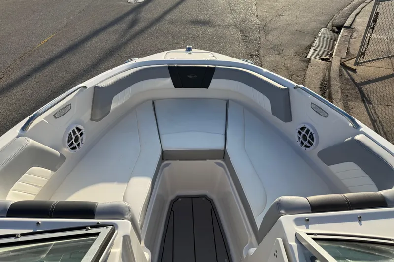 Slide: The Image of 2022 Chaparral 21 SSi boat interior with white seating and speakers, docked on pavement. - 6