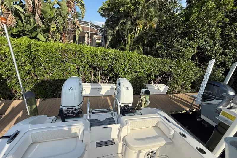 Slide: The Image of 2019 Twin Vee 26 Center Console boat with dual engines docked near lush greenery. - 8