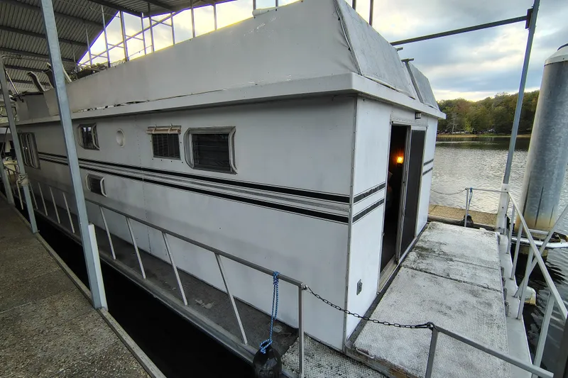 Slide: The Image of 1981 Lazy Days 50 houseboat docked by a serene lake under a covered marina. - 10