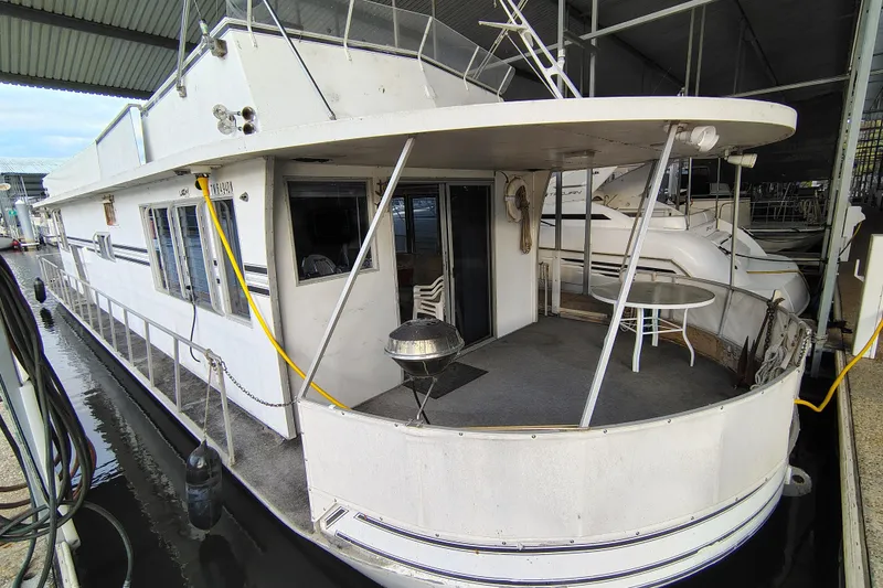 Slide: The Image of 1981 Lazy Days 50 houseboat docked in a covered marina, featuring a spacious deck area. - 11
