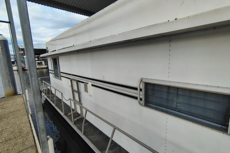 Slide: The Image of 1981 Lazy Days 50 houseboat docked at marina, side view with windows and railing. - 12