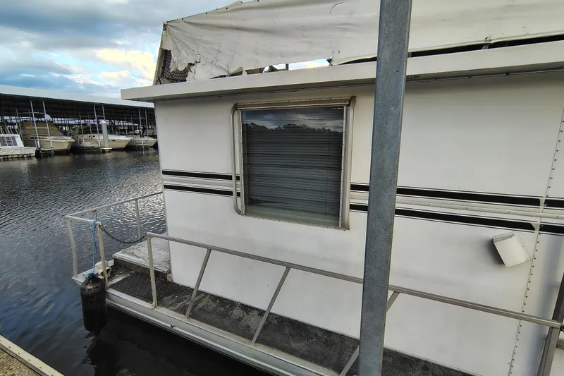 Slide: The Image of 1981 Lazy Days 50 houseboat docked at marina, featuring weathered exterior and calm waters. - 13