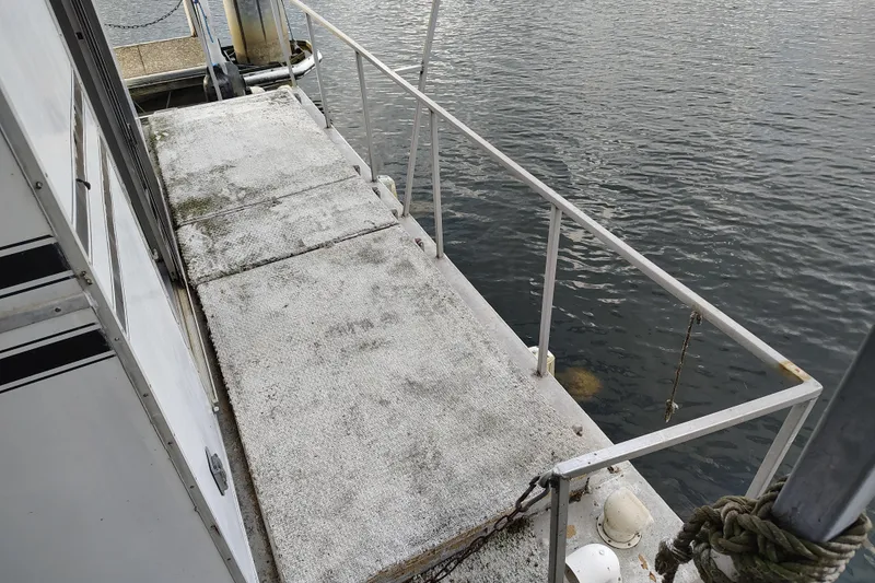 Slide: The Image of Deck of 1981 Lazy Days 50 houseboat with railing, docked on calm water. - 14