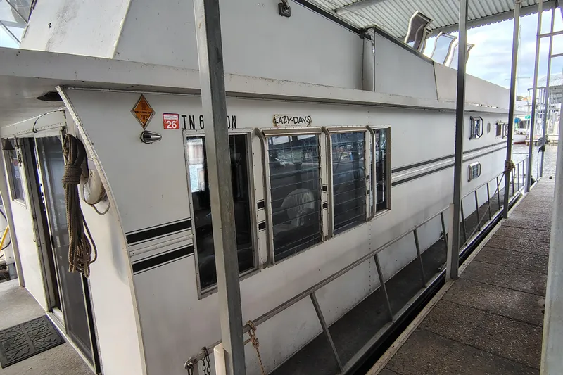 Slide: The Image of 1981 Lazy Days 50 houseboat docked, featuring white exterior and multiple windows. - 5