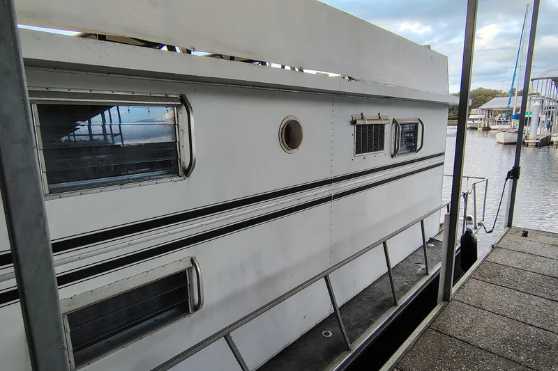 Slide: The Image of 1981 Lazy Days 50 houseboat docked, featuring multiple windows and a serene waterfront view. - 8