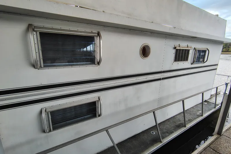 Slide: The Image of 1981 Lazy Days 50 houseboat with windows and railing, docked by the water. - 9