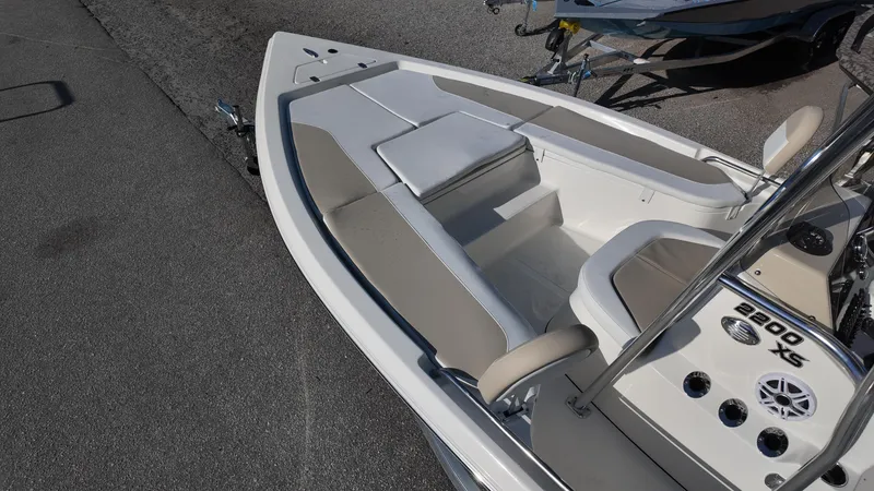 Slide: The Image of 2025 Bulls Bay 2200XS boat interior with seating and console, parked on pavement. - 10