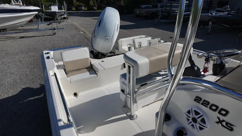 Slide: The Image of 2025 Bulls Bay 2200XS boat interior with seating and motor, parked on gravel. - 13