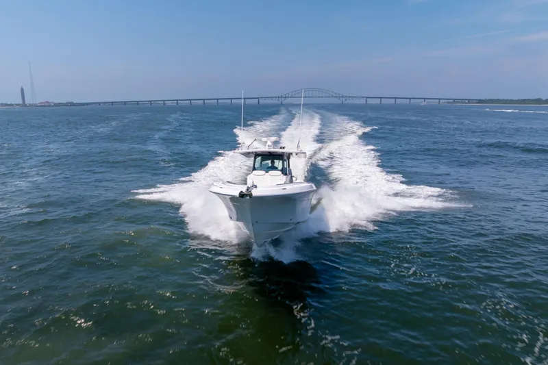 Slide: The Image of 2026 HCB 42 Lujo boat cruising on open water with bridge in background. - 30