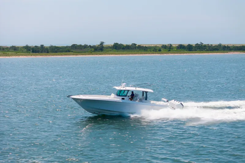 Slide: The Image of 2026 HCB 42 Lujo boat cruising on open water, near a lush shoreline. - 31