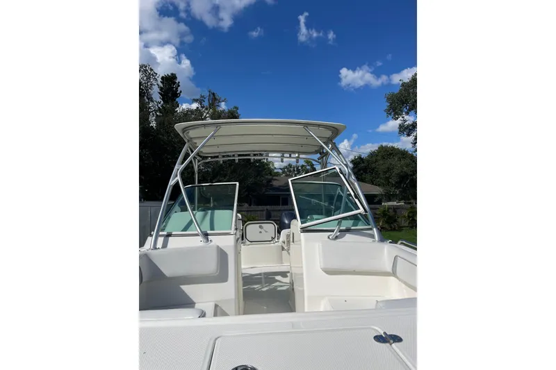 Slide: The Image of 2016 Carolina Cat 230 DC boat with open deck and canopy under blue sky. - 20