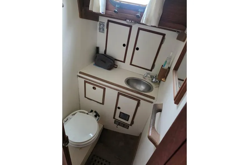 Slide: The Image of 1981 Cape Dory 36 yacht bathroom with sink, toilet, and storage cabinets. - 2