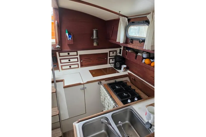 Slide: The Image of 1981 Cape Dory 36 yacht kitchen with stove, sink, and wooden cabinetry. - 5
