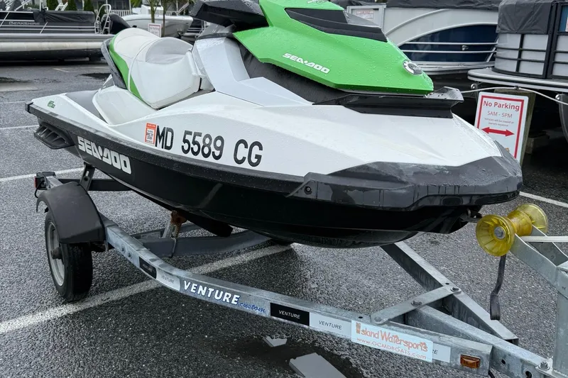 Slide: The Image of 2013 Sea-Doo GTI 130 on trailer in parking lot, green and white design. - 2