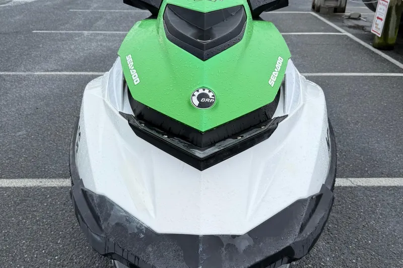Slide: The Image of 2013 Sea-Doo GTI 130 jet ski with green and white design in parking lot. - 3