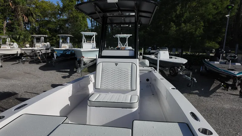 Slide: The Image of 2026 Twin Vee 22 Bay Cat boat with sleek seating, parked among other boats. - 15