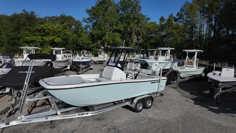 Slide: The Image of 2026 Twin Vee 22 Bay Cat boat on trailer, surrounded by other boats, in a sunny outdoor setting. - 3
