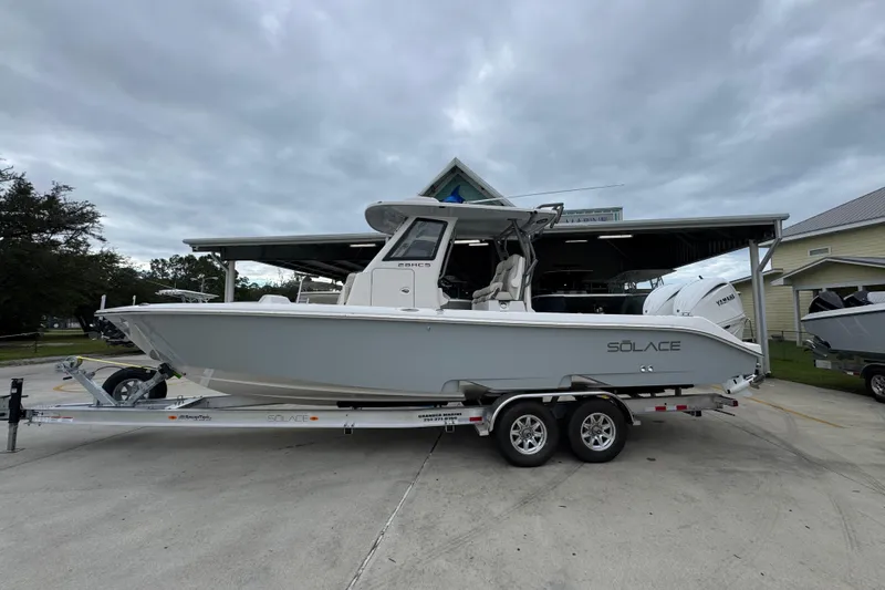 Slide: The Image of 2026 Solace 28 HCS boat on trailer, parked outdoors under cloudy sky. - 1
