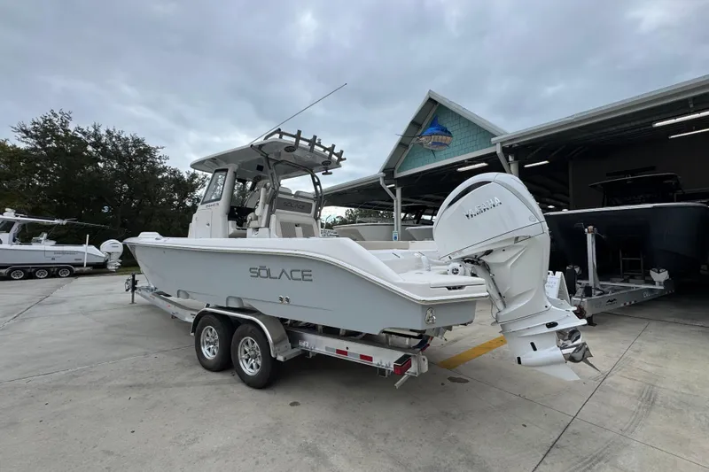 Slide: The Image of 2026 Solace 28 HCS boat on trailer, parked outdoors near a building. - 14