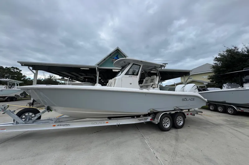 Slide: The Image of 2026 Solace 28 HCS boat on trailer, parked outdoors under cloudy sky. - 2