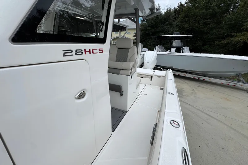 Slide: The Image of 2026 Solace 28 HCS boat, sleek design, white exterior, comfortable seating, parked outdoors. - 22