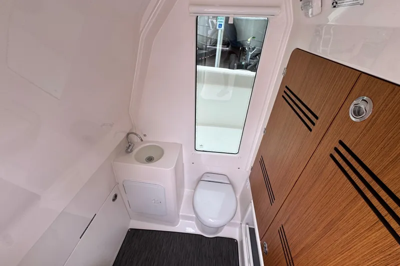 Slide: The Image of Interior of 2026 Solace 28 HCS boat bathroom with sink, toilet, and wooden cabinetry. - 25