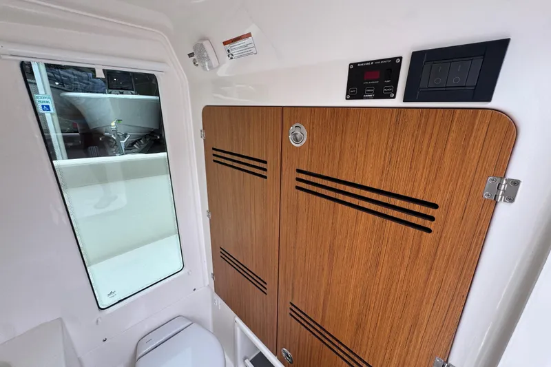Slide: The Image of Interior of 2026 Solace 28 HCS boat, featuring wooden cabinet and control panel. - 26