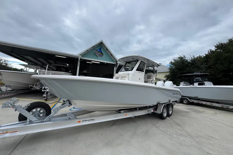Slide: The Image of 2026 Solace 28 HCS boat on trailer, parked outdoors under cloudy sky. - 3