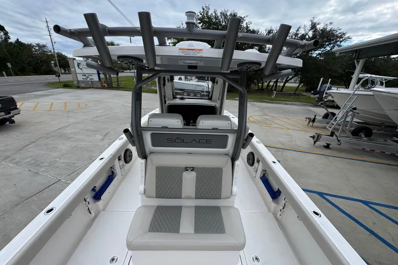Slide: The Image of 2026 Solace 28 HCS boat interior with seating and helm, parked outdoors. - 36