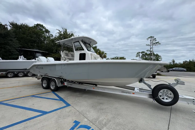 Slide: The Image of 2026 Solace 28 HCS boat on trailer, parked outdoors under cloudy sky. - 7